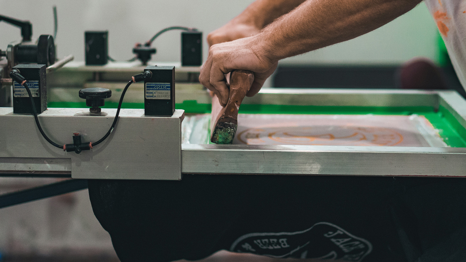 Silkscreen printing process being applied to fabric for corporate gift printing, part of custom printing service offerings.