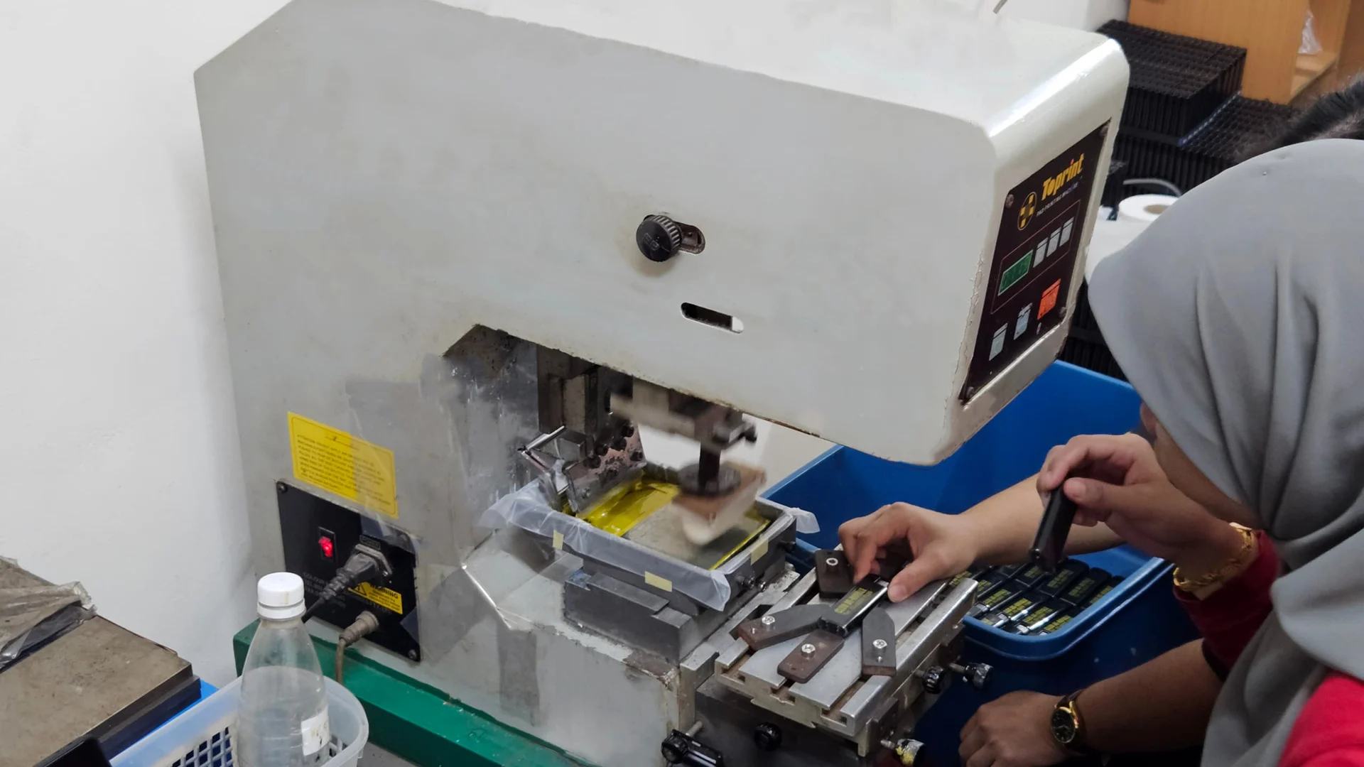 Technician using pad printing machine for small promotional items, highlighting detailed custom printing services for corporate gifts.