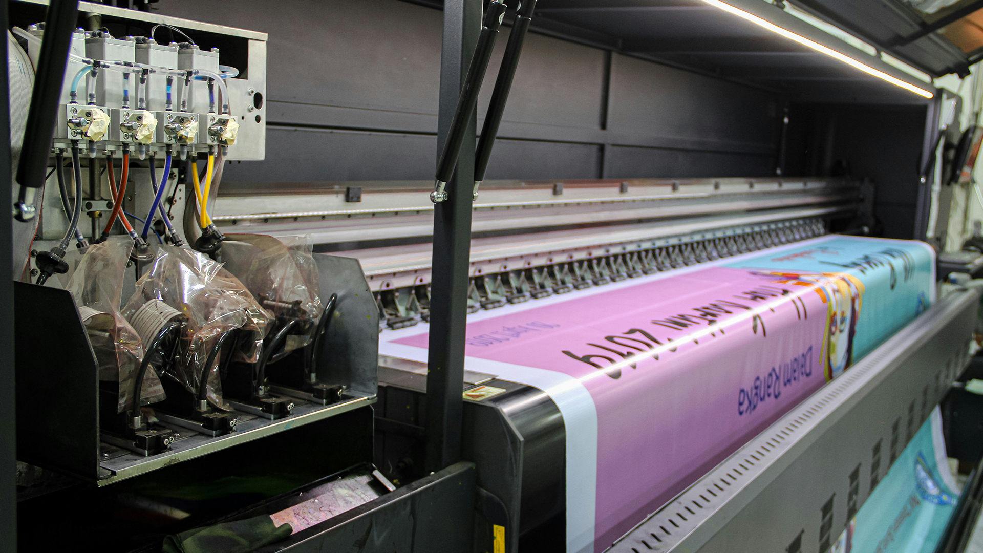 Large format printer creating a colorful banner, part of a full-service corporate gift printing and custom printing solution.