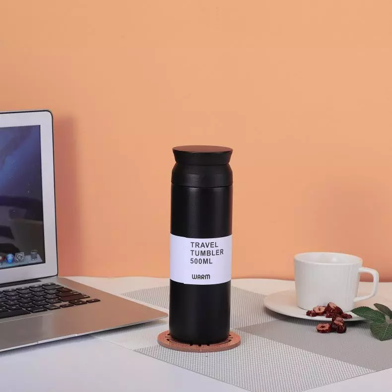 black custom vacuum flask or travel tumbler in 500ml placed center laptop and coffee cup
